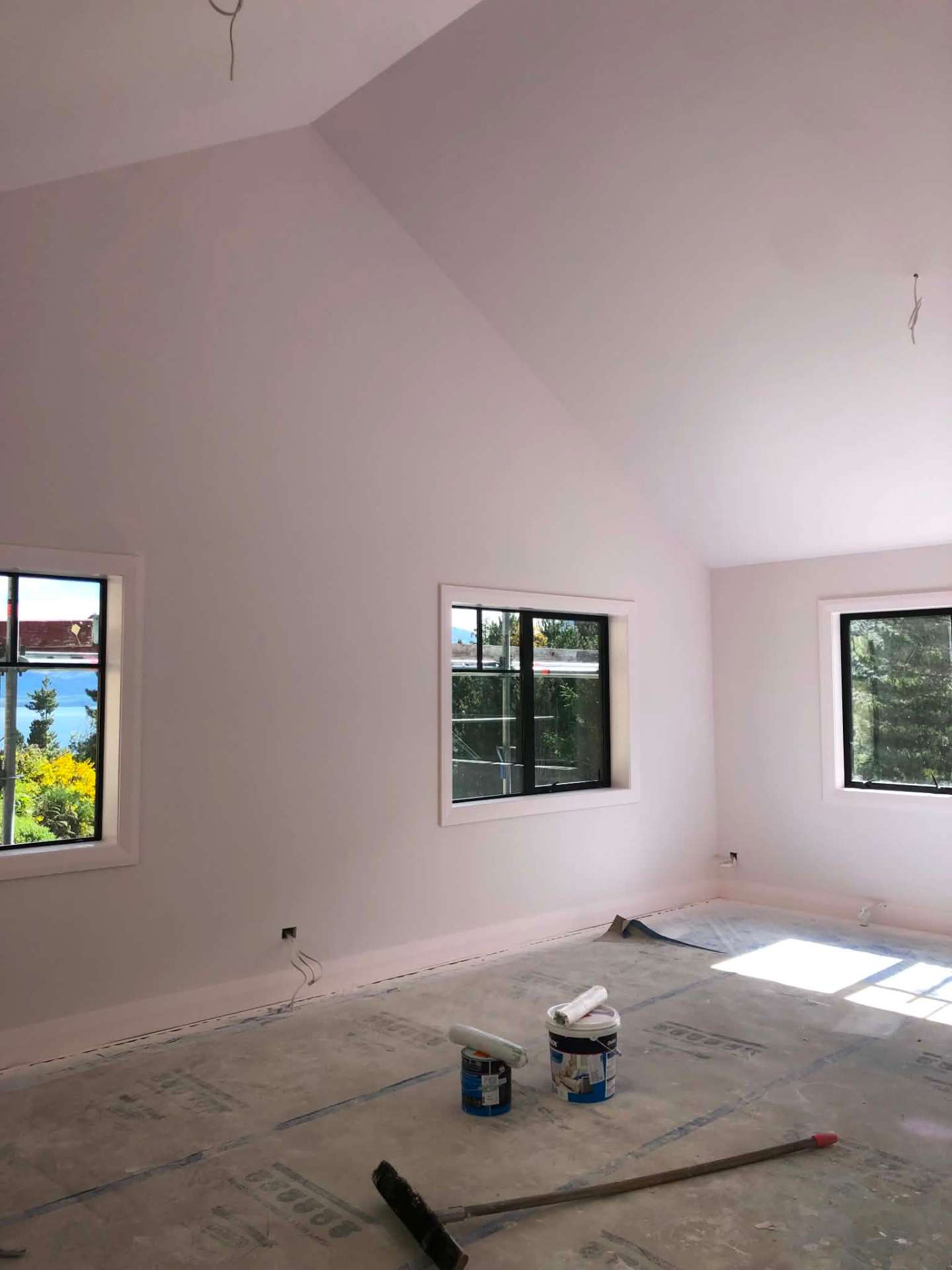 Vaulted bedroom mid-paint with fresh white walls and ceiling