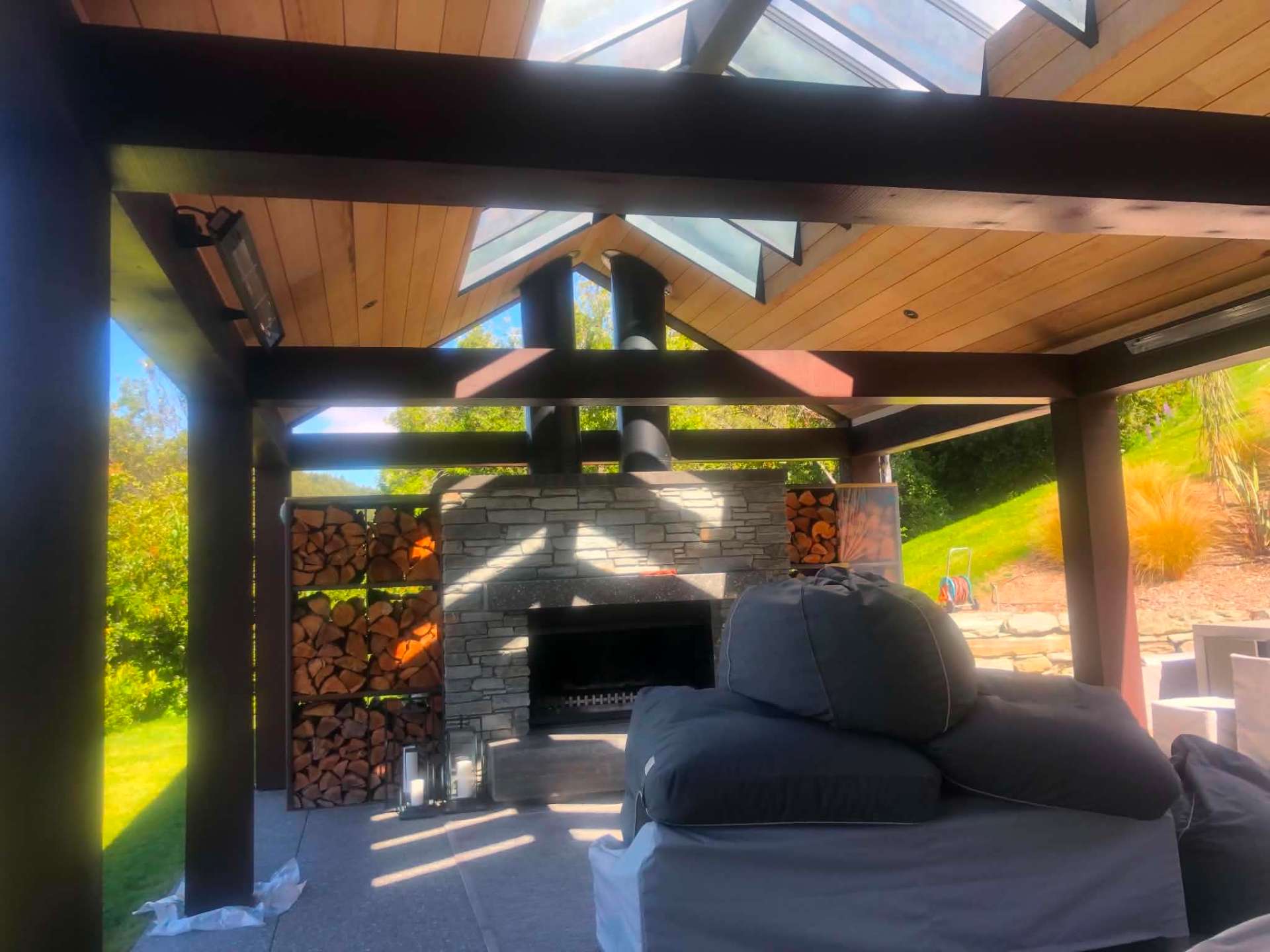 Outdoor pavilion with dark stained beams and stone fireplace