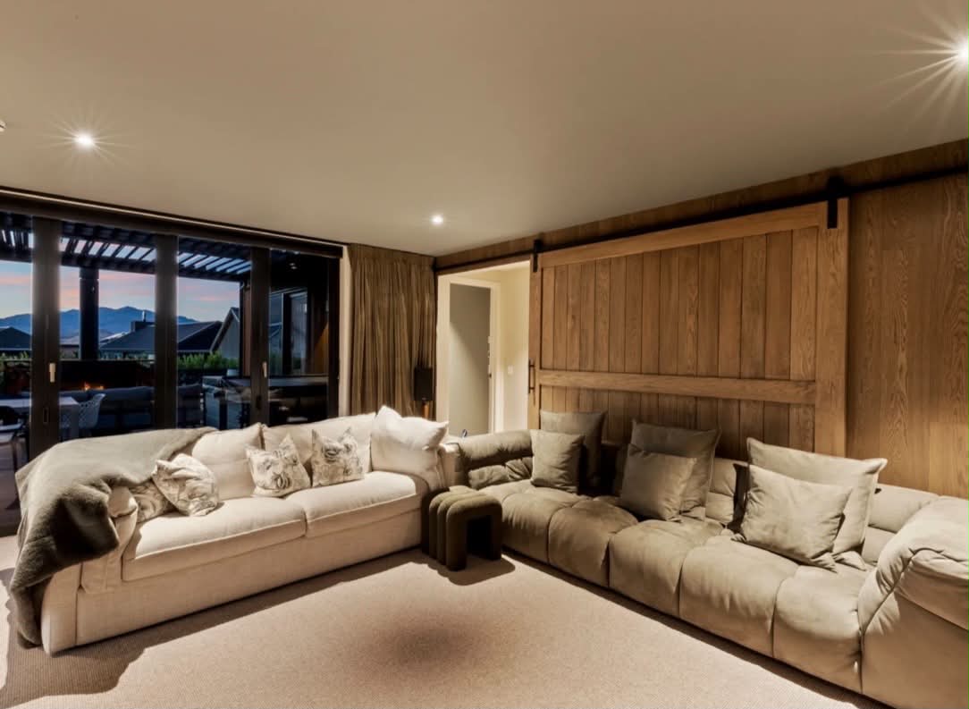 Media lounge with warm timber panelling and neutral walls