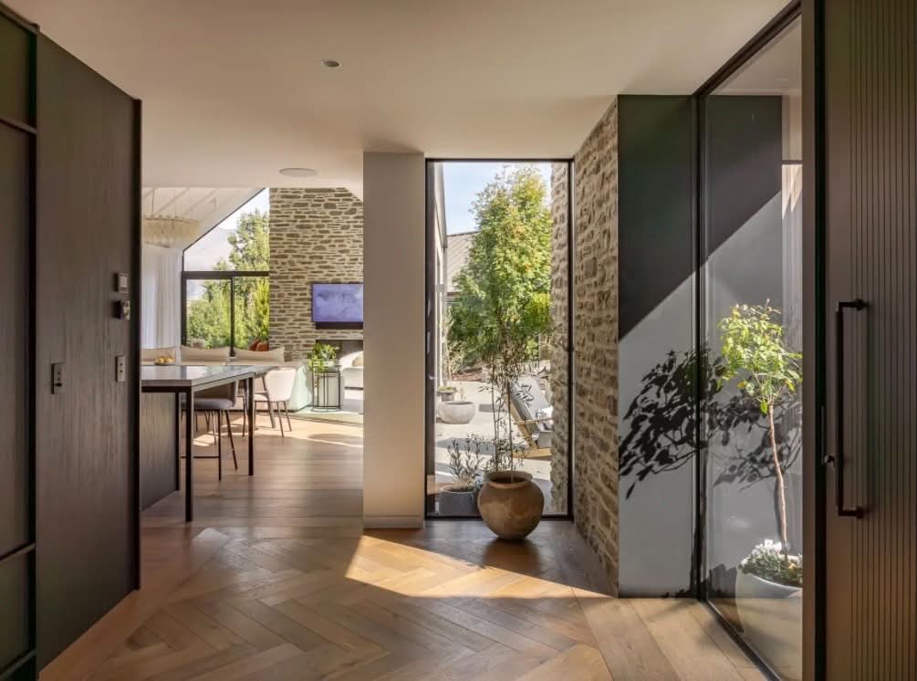 Modern entryway with herringbone oak floors and stone feature wall