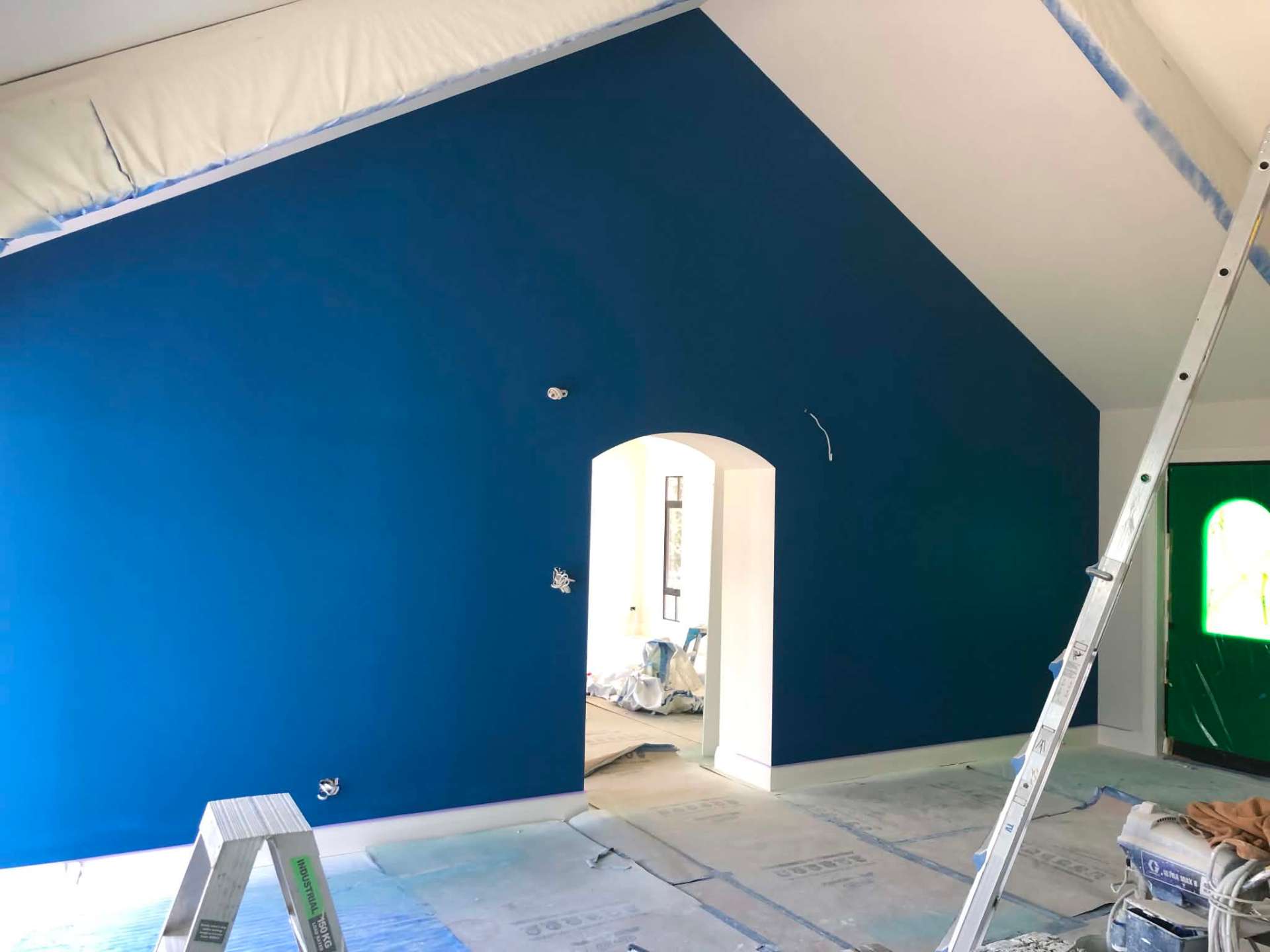 Vaulted room mid-paint with deep navy feature wall and archway
